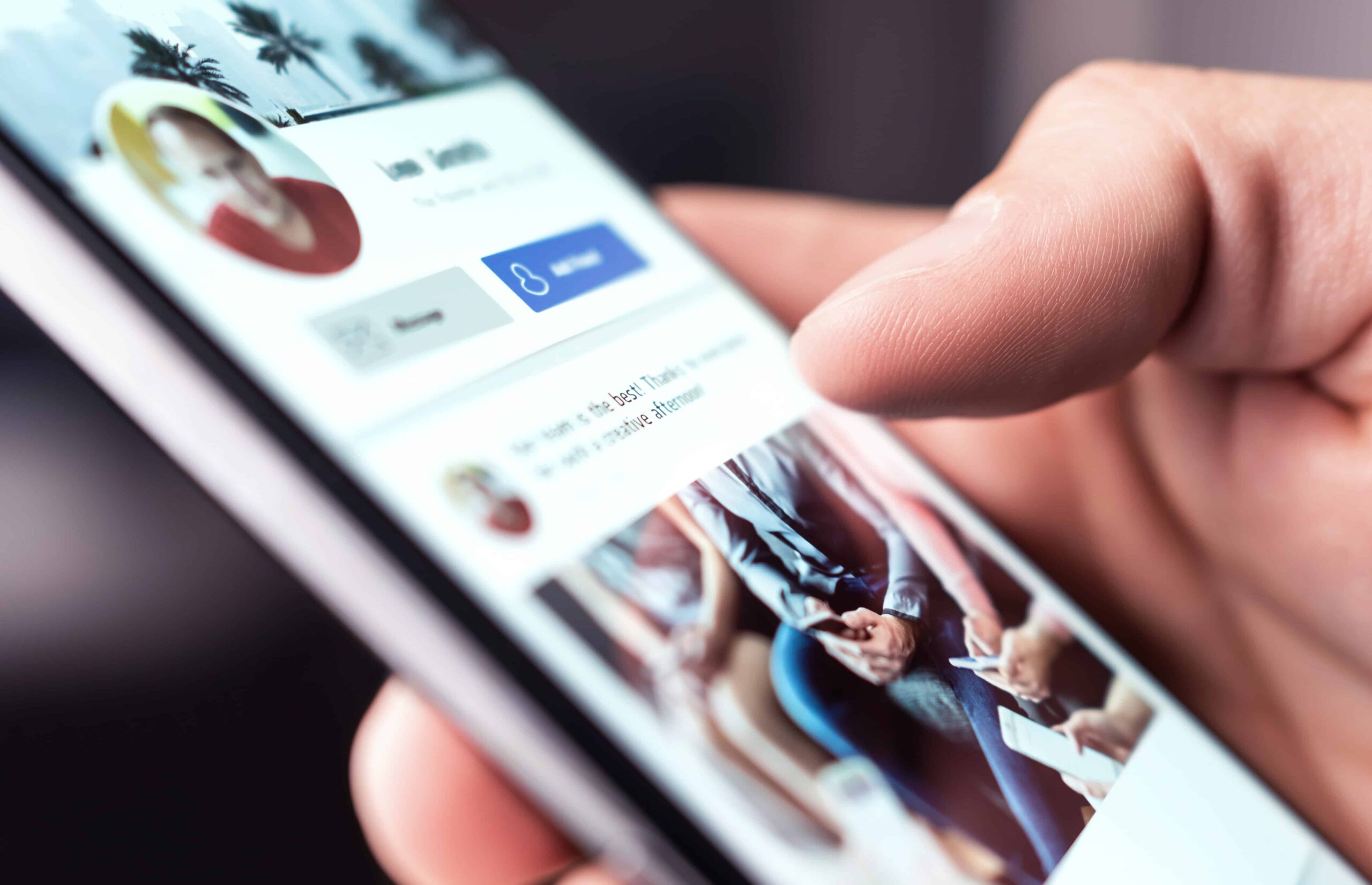 A hand scrolling through a social media profile on a smartphone screen, highlighting online activity and digital engagement.