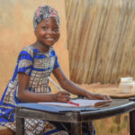 Girl is outside with items on a table and smiling