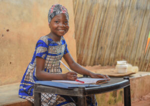 Girl is outside with items on a table and smiling