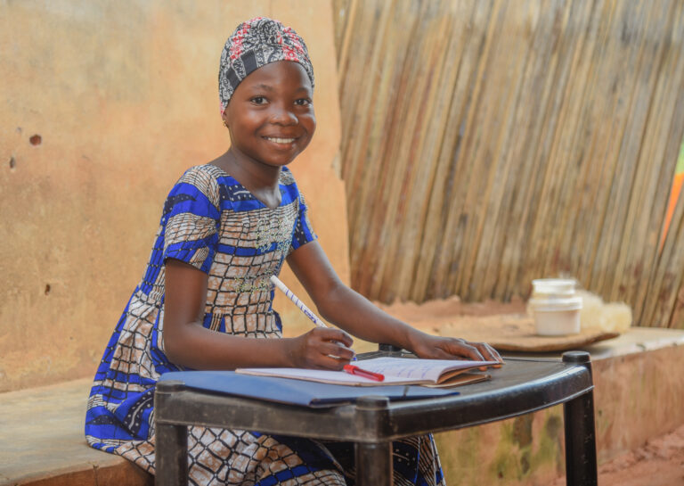 Girl is outside with items on a table and smiling