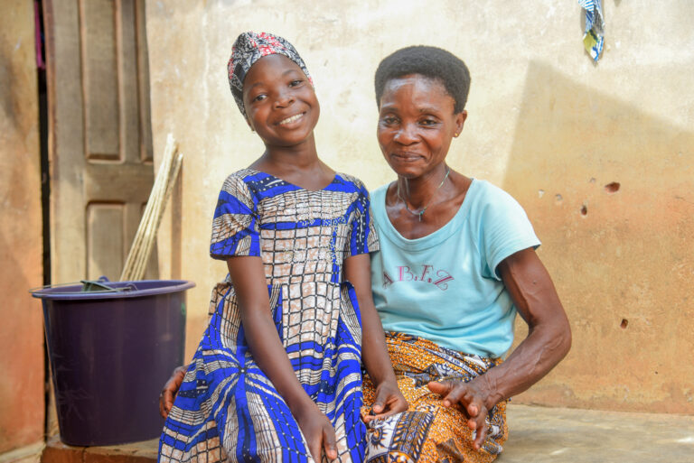 Adult woman and female child sit together outside