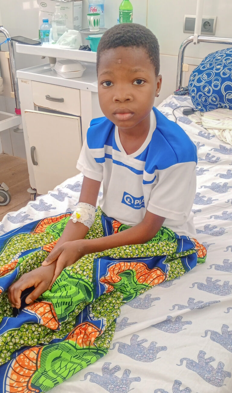 Girl sits in a hospital bed in Benin, where she received lifesaving care.
