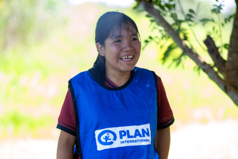 Girl wearing soccer jersey with Plan International logo
