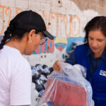 Plan International staff member distributing resources.