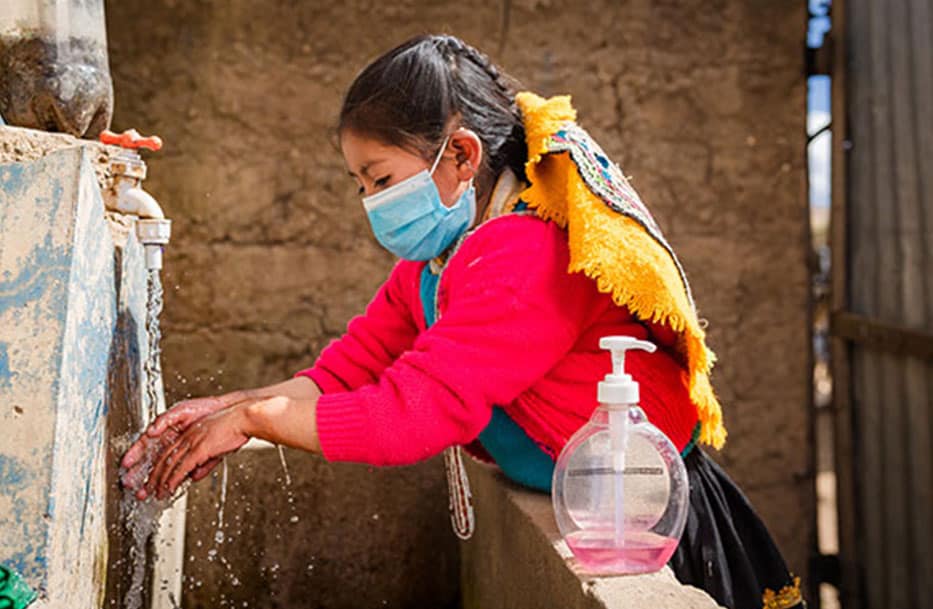 A girl using a water hygiene station washing her hands