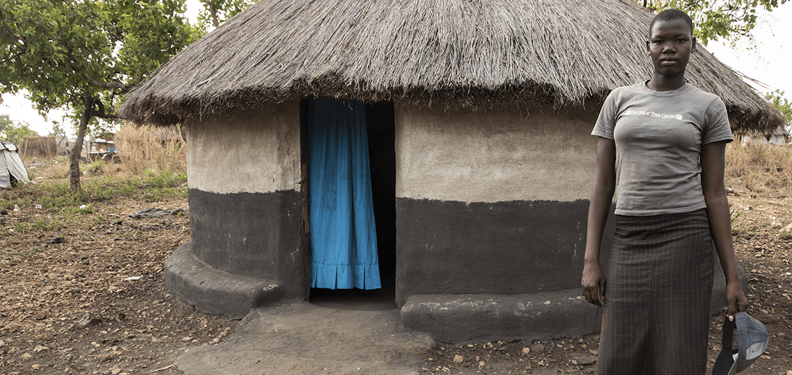 Stella, a girl living in the Bidi Bidi refugee camp in north Uganda, in front of her home
