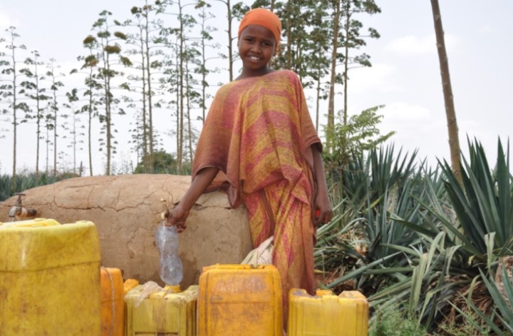Anisa stands at the water pump