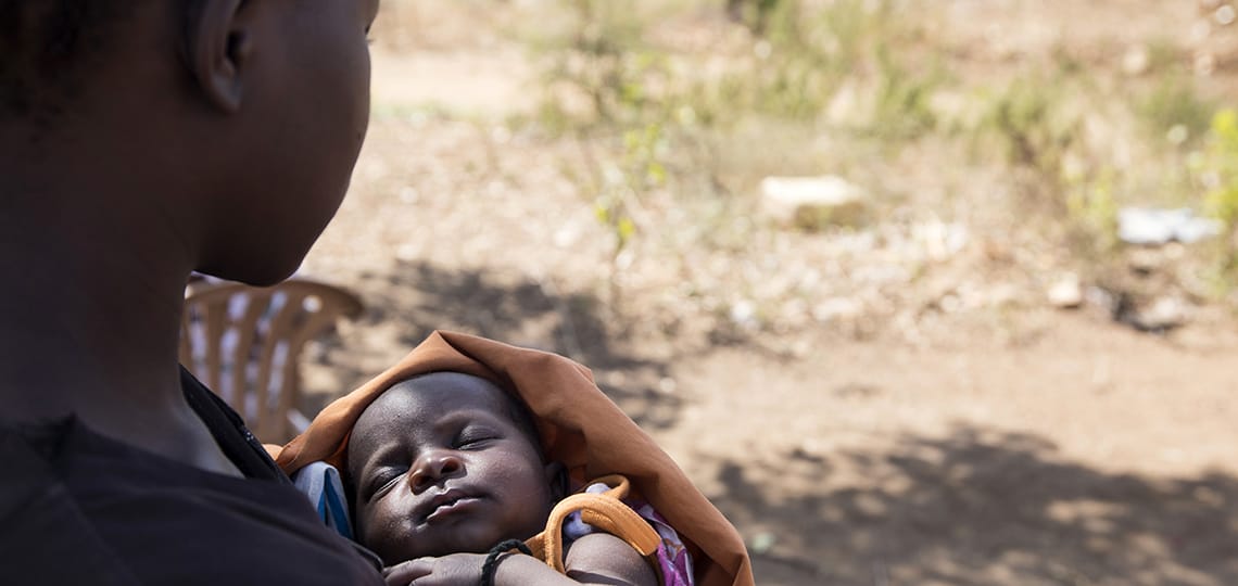 Faith, a girl living in the Bidi Bidi displaced persons camp in north Uganda, holds her new baby