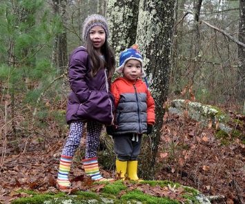 Two children in winter clothes in a wooded area, but neither should be limited by girl or boy stereotypes and gender labels
