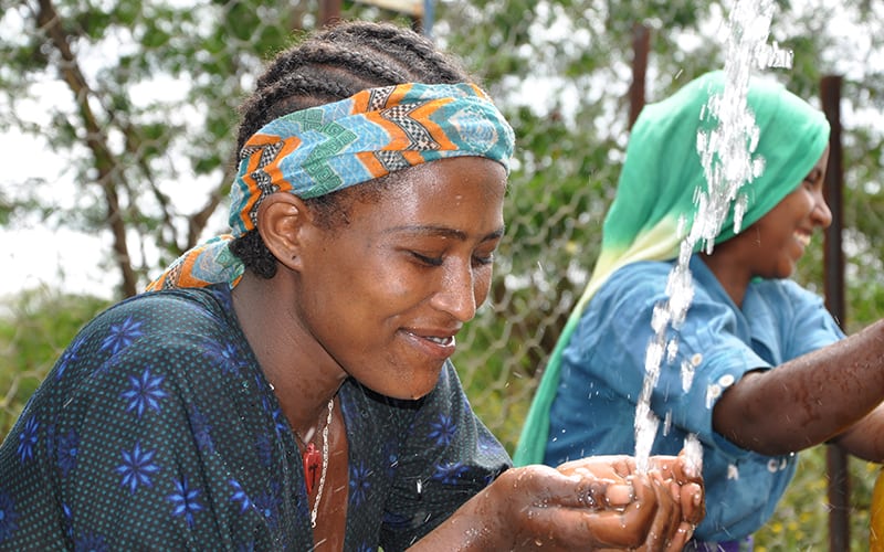 Clean water running into a young woman’s hands, protecting her from disease, and school days missed in favor of hauling water