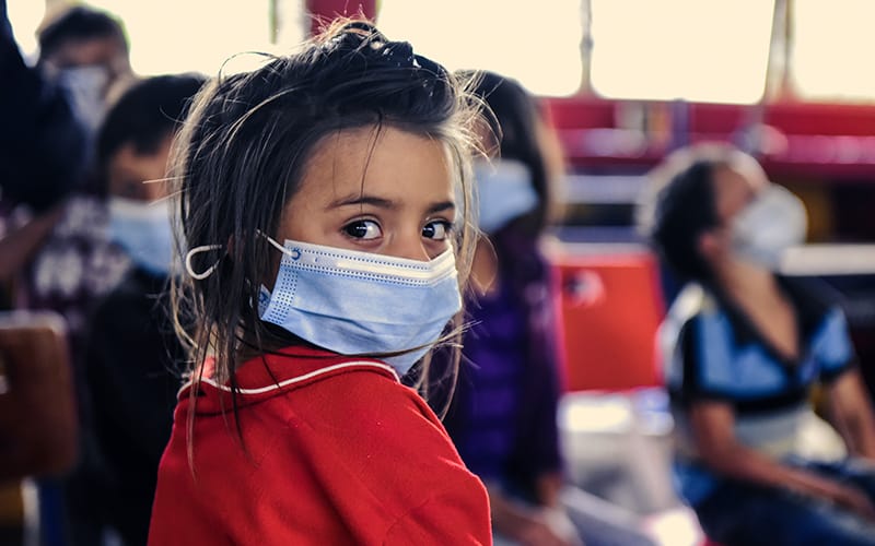 A little girl in a medical mask is protected from disease, disaster, and trafficking
