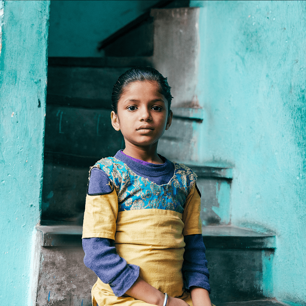 Priya, age 8, lives in Dehli, India, pictured here sitting on stairs