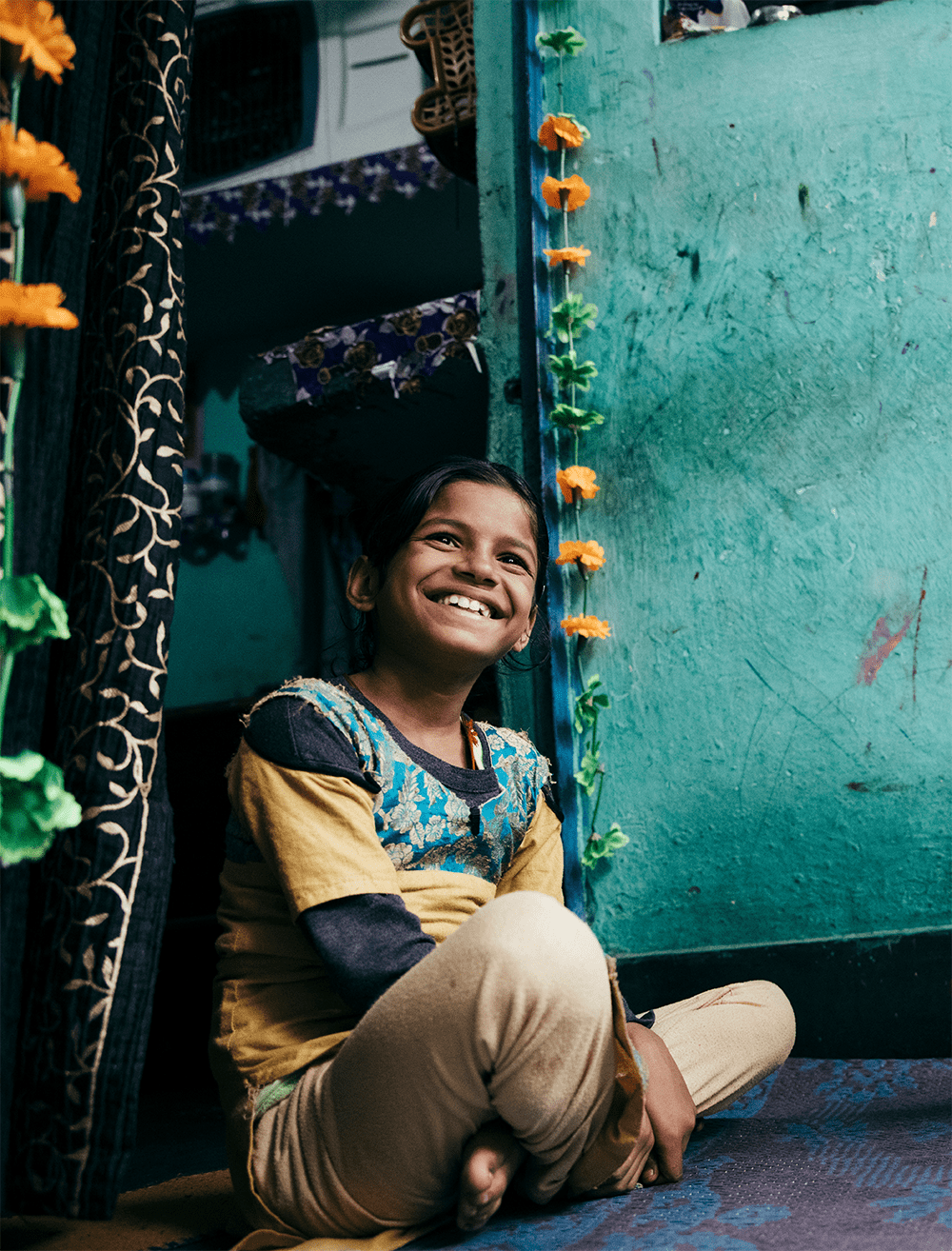 Priya, age 8, lives in Dehli, India, pictured here sitting and smiling