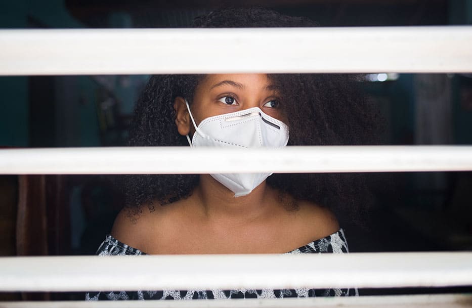 A girl looks out from an indoor quarantine as COVID vaccines are distributed around the world