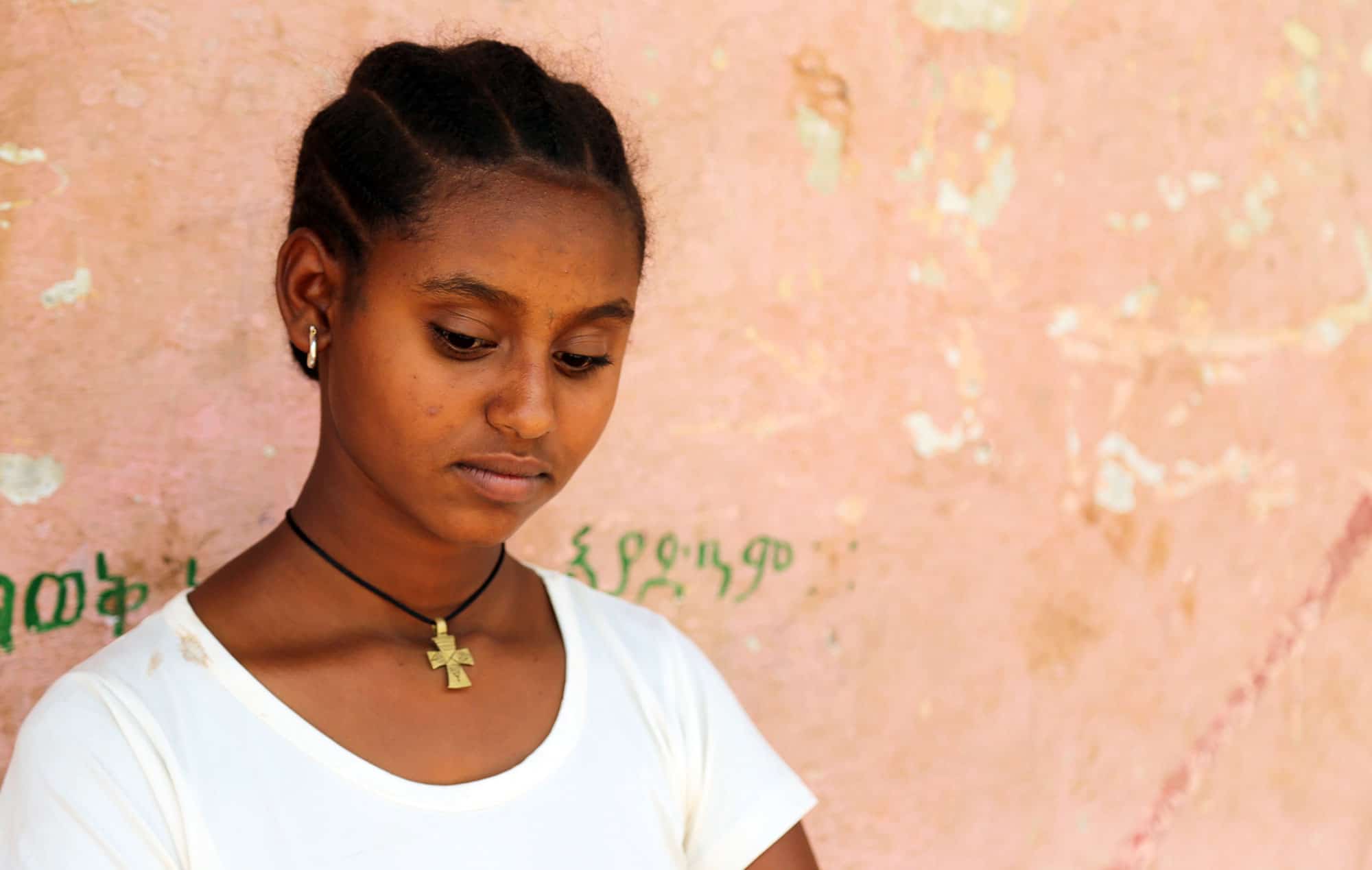 Worke, a girl in Ethiopia, looks down thinking about her need for clean water, sanitary pads, and education.