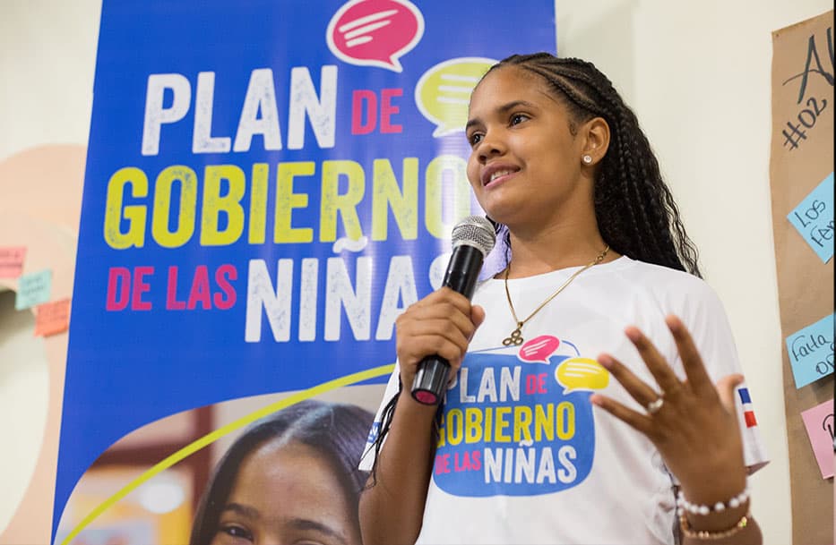 Woman on a microphone speaks about root causes of girls' insecurity and need for protection in Central America