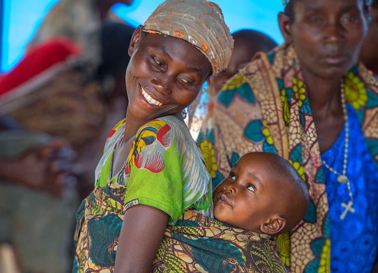 A young mother smiles over her shoulder at her baby on mom's back