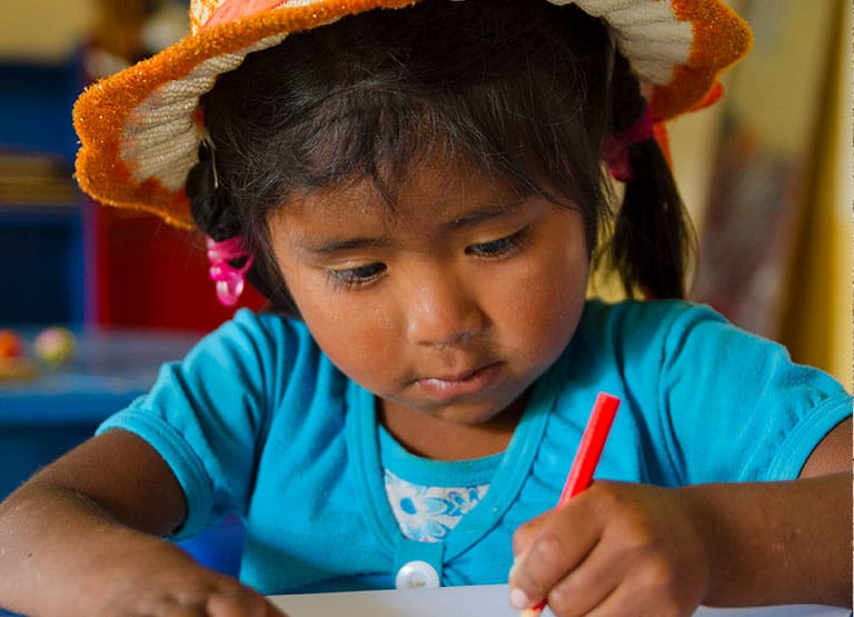 Young girl writes with a red pencil