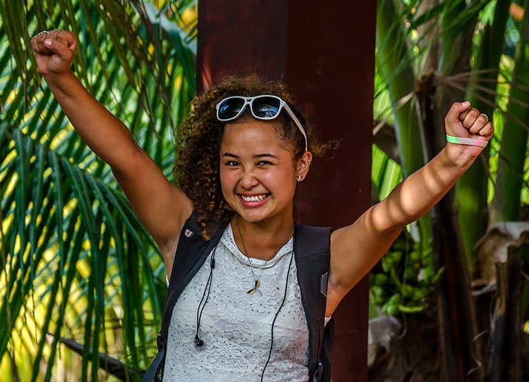 Teen girl celebrates with a smile and raised arms