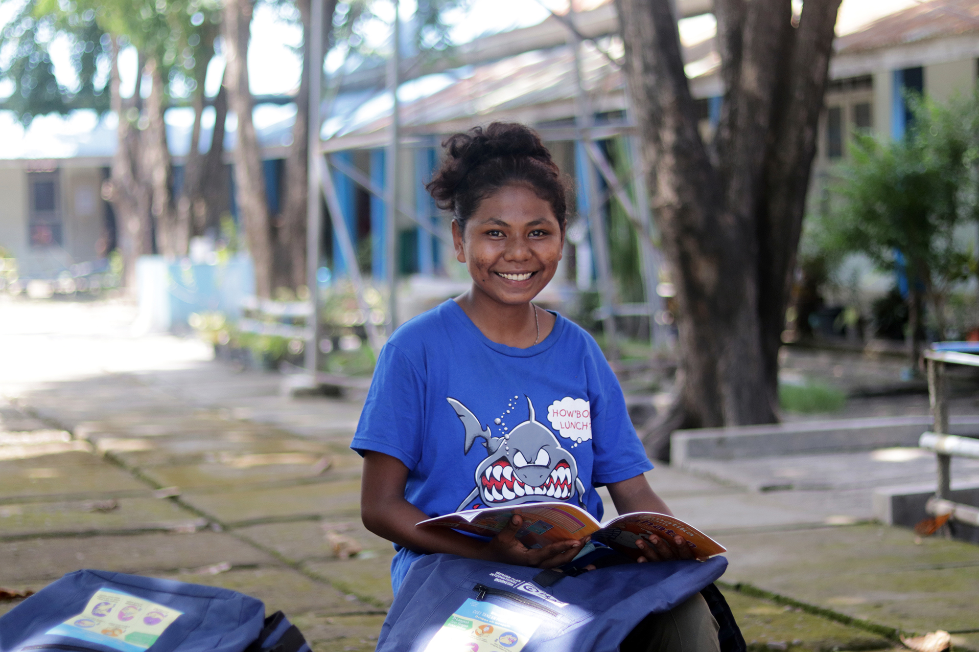 Girl living in temporary shelter after Cyclone Seroja in Indonesia reads her school book