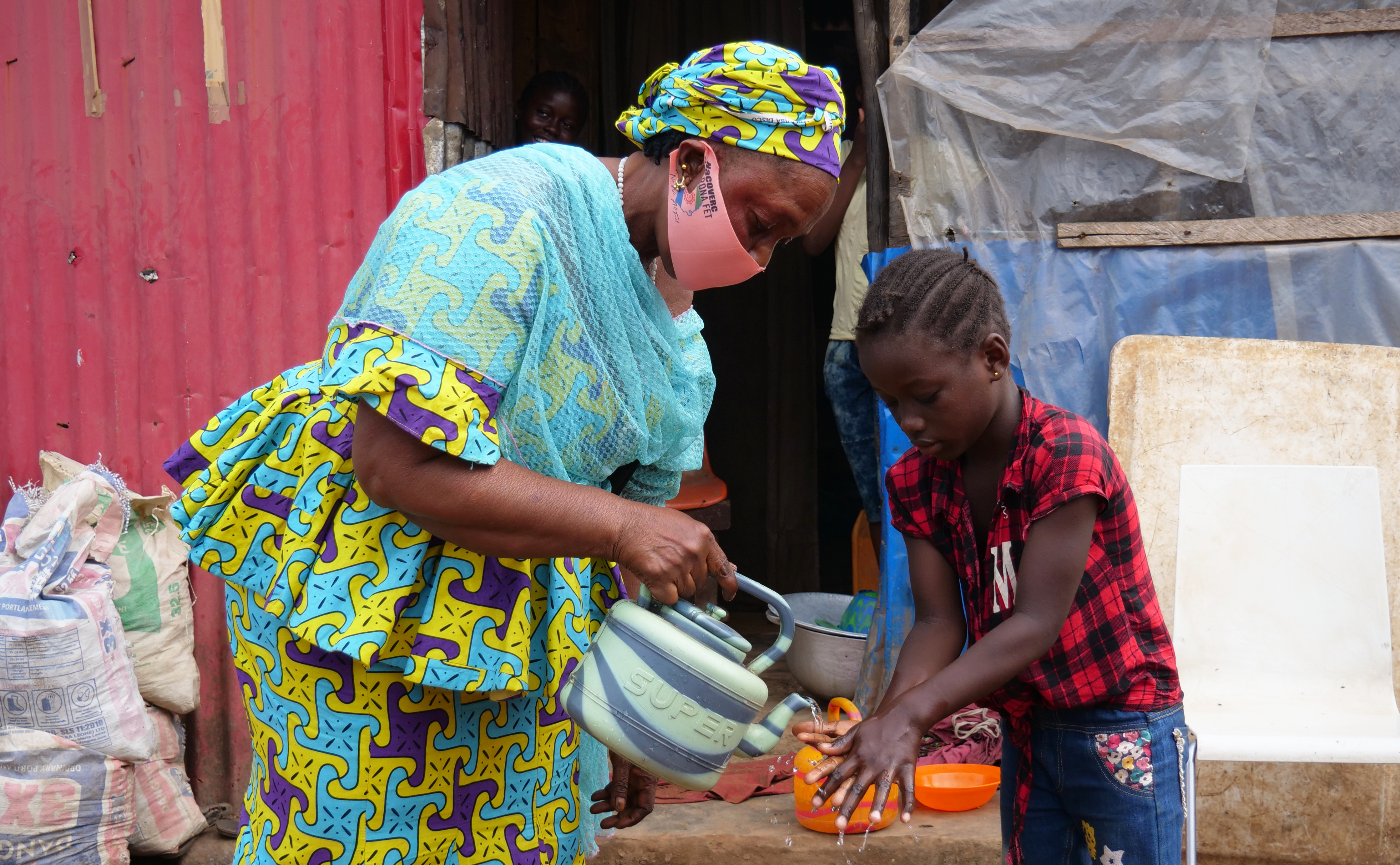 Young woman and girl wash their hands after the Ebola Virus outbreak in 2014 in Freetown, Sierra Leone, Africa.