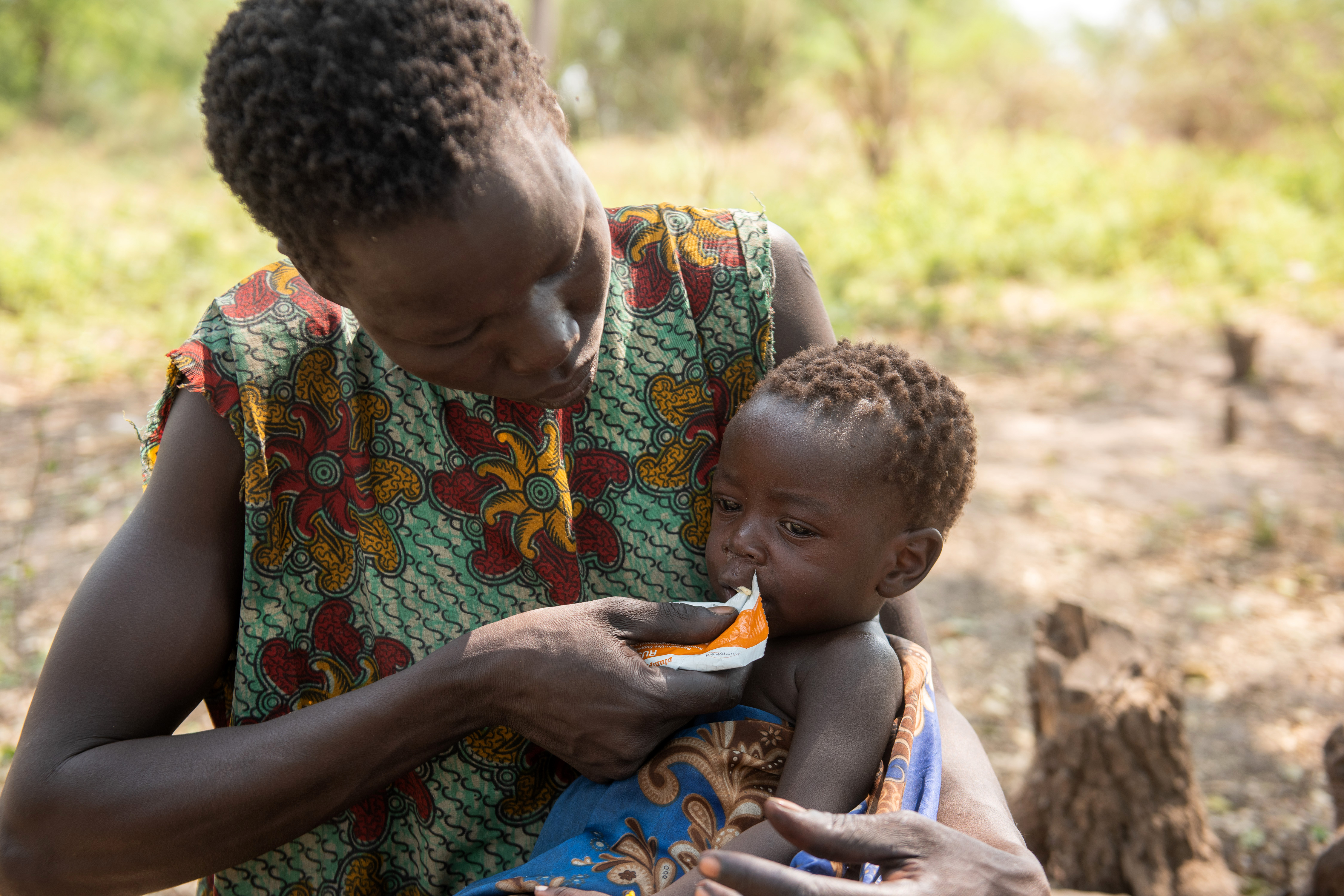 A young South Sudanese mother in Pibor country feeds her child, fighting malnutrition among young children and women.