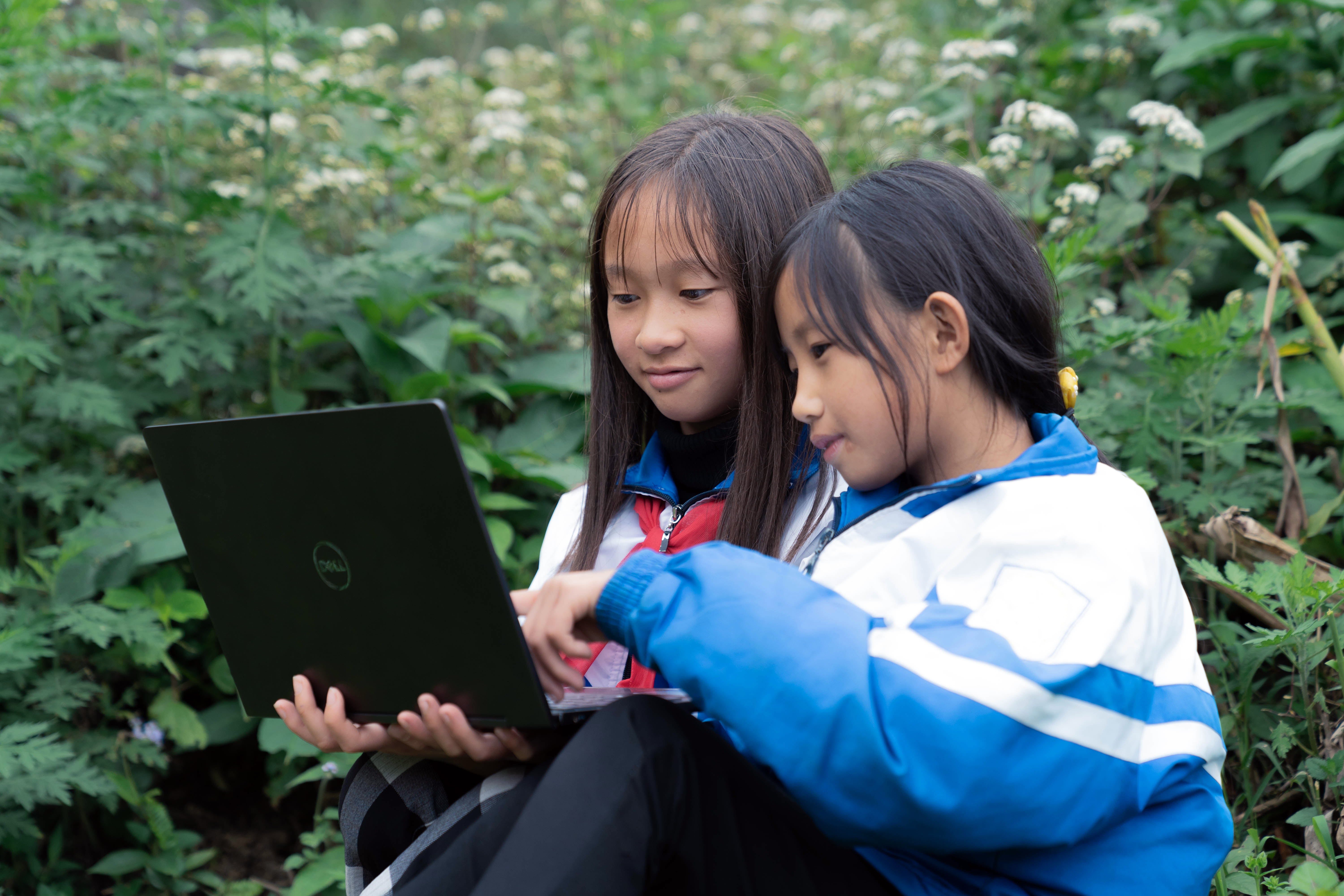 Two girls in Vietnam look at a laptop while Plan works to help keep girls safe from harassment online