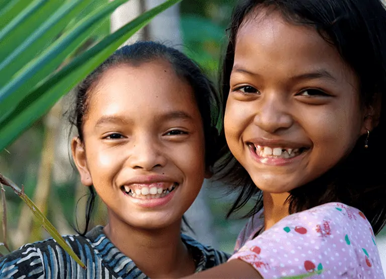 Two smiling girls from Plan USA's planned giving report