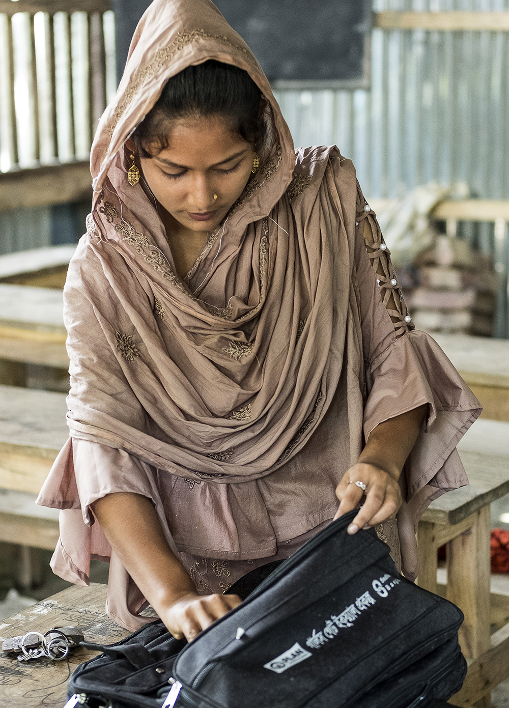 Tanzila, a young woman in Bangladesh, zips her school bag.