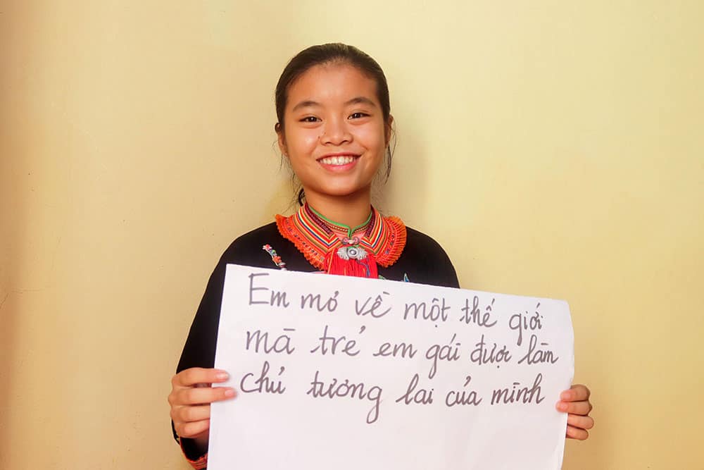 Huyen holds a sign that says, "I dream of a world where girls are owners of their futures."