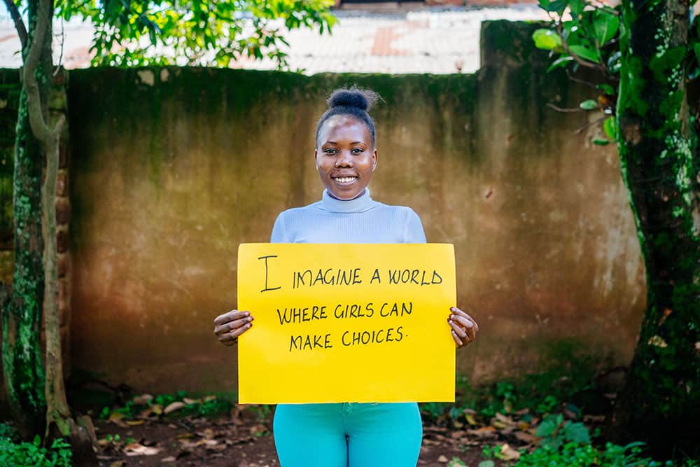 Mastula holds a sign that says, "I imagine a world where girls can make choices."