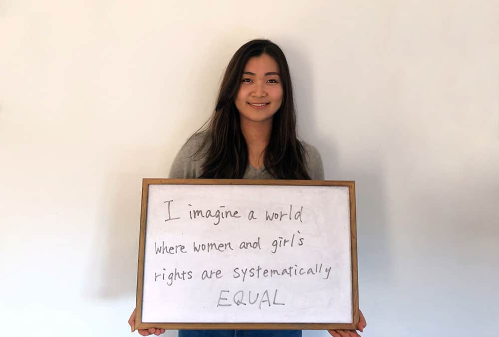 Mika holds a sign that says, "I imagine a world where women and girls’ rights are systematically equal."