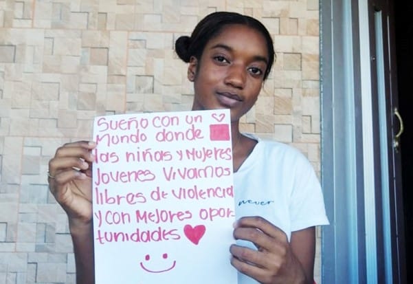 Yulieth holds a sign that says, "I dream of a world where girls and young women live free from violence and with better opportunities."