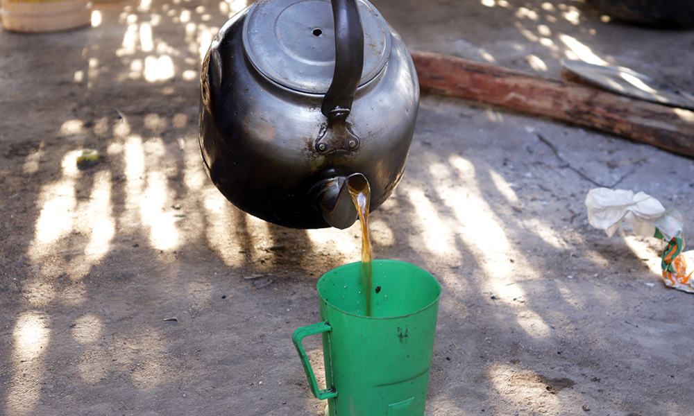 Nasra pours a cup of black tea, sometimes the only sustenance that she and her family get all day.