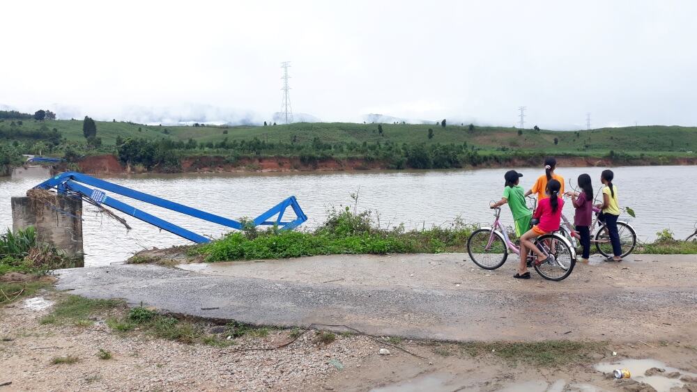Children stand on one side of a destroyed bridge after a typhoon in Vietnam swept it away.