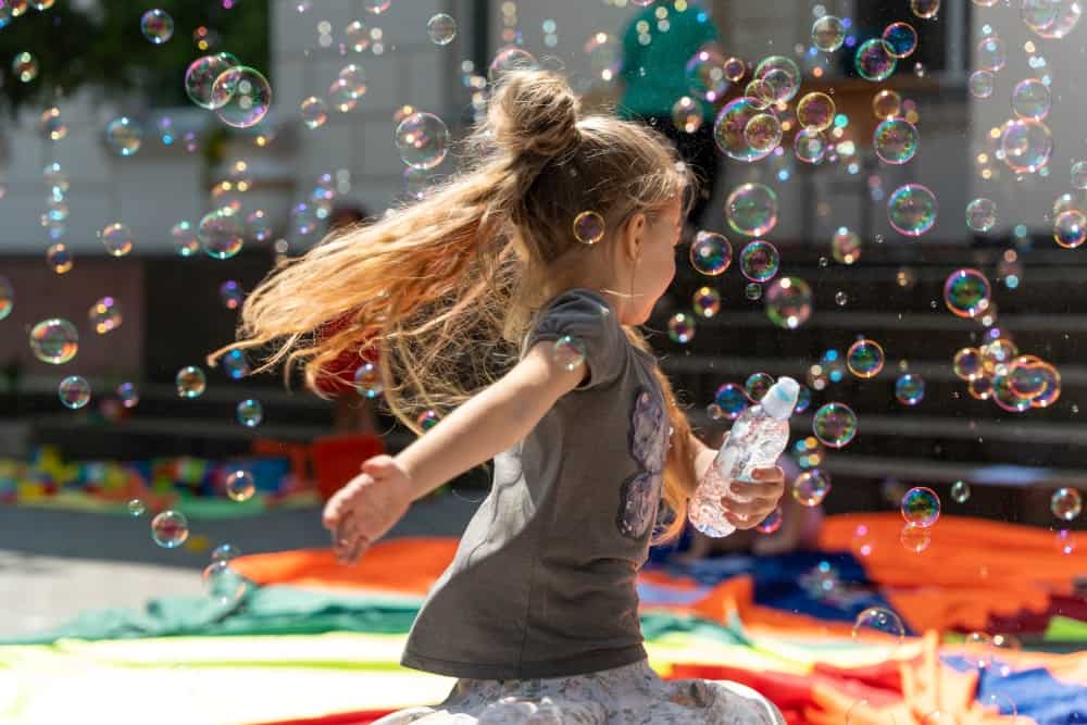 A girl runs through bubbles created by one of the toys brough by the Ludobus team.