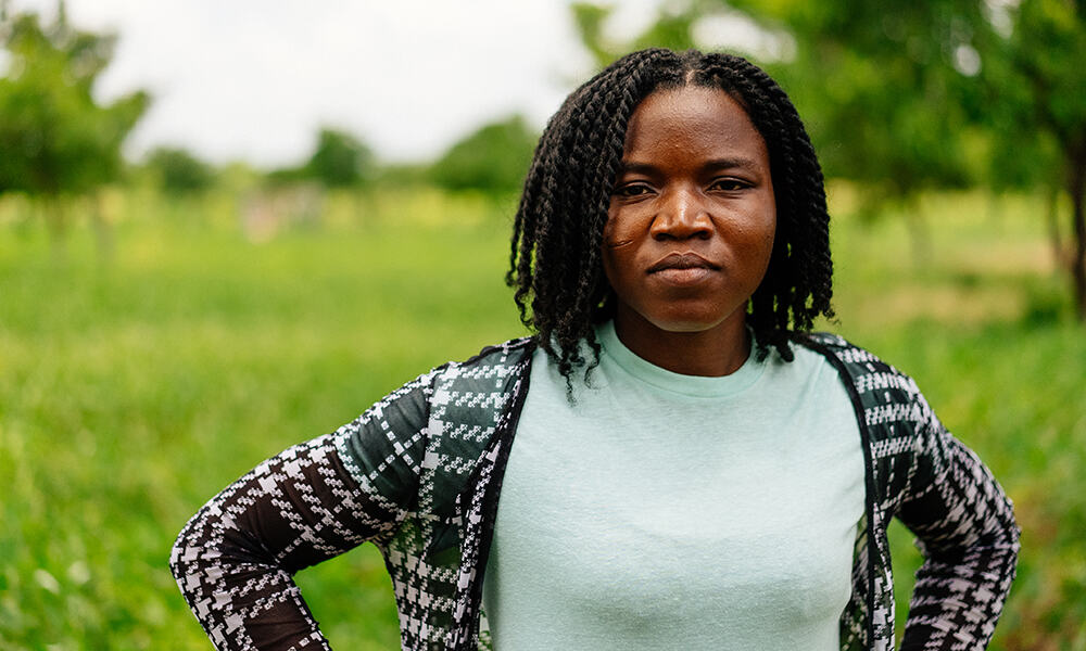 Doris, a 27-year-old maize and soybean farmer, stands on her 14 acres of farm land.  