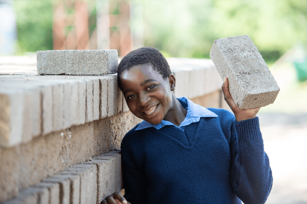 A girl in Zimbabwe holding a brick in her hand