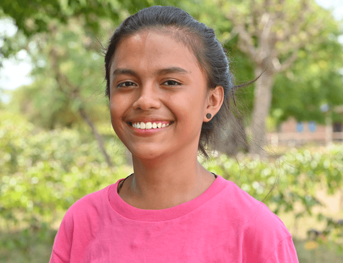 Chanda, a 16-year-old girl from Indonesia, wears a pink shirt and smiles for the camera. 