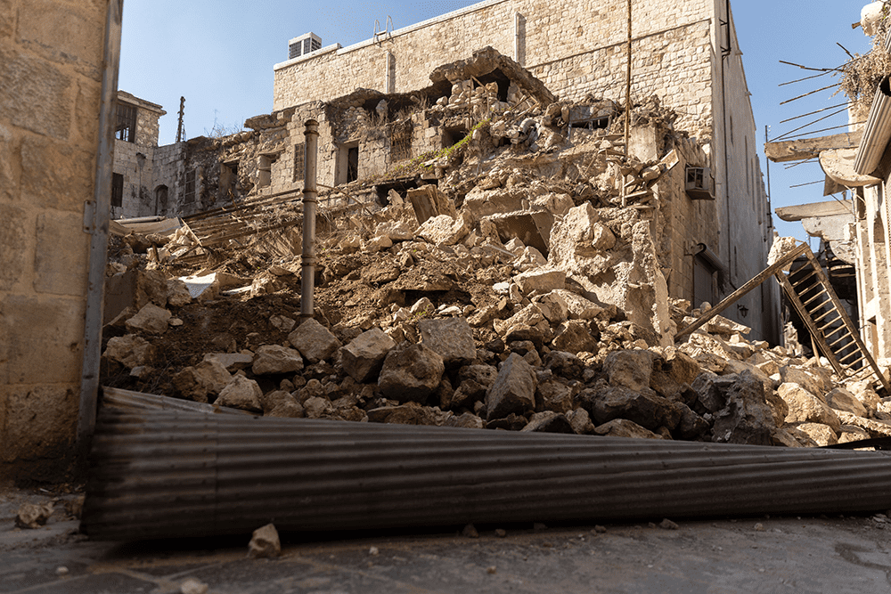 A pile of concrete from a collapsed building in between two damaged but intact buildings in the city of Aleppo. 