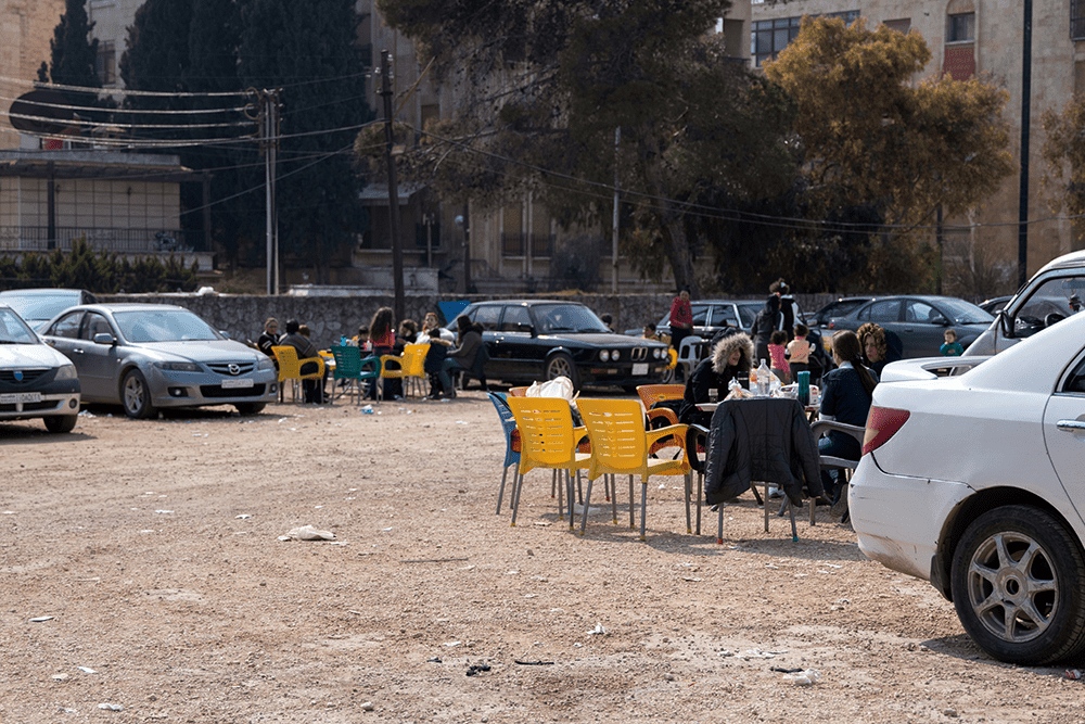 A parking lot filled with cars and colorful chairs where families are staying after the earthquakes.