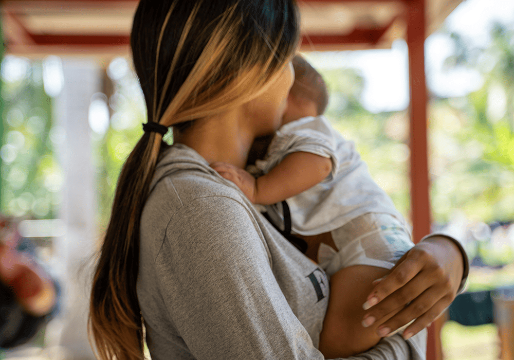 Francisca holds her infant son and looks away from the camera. 