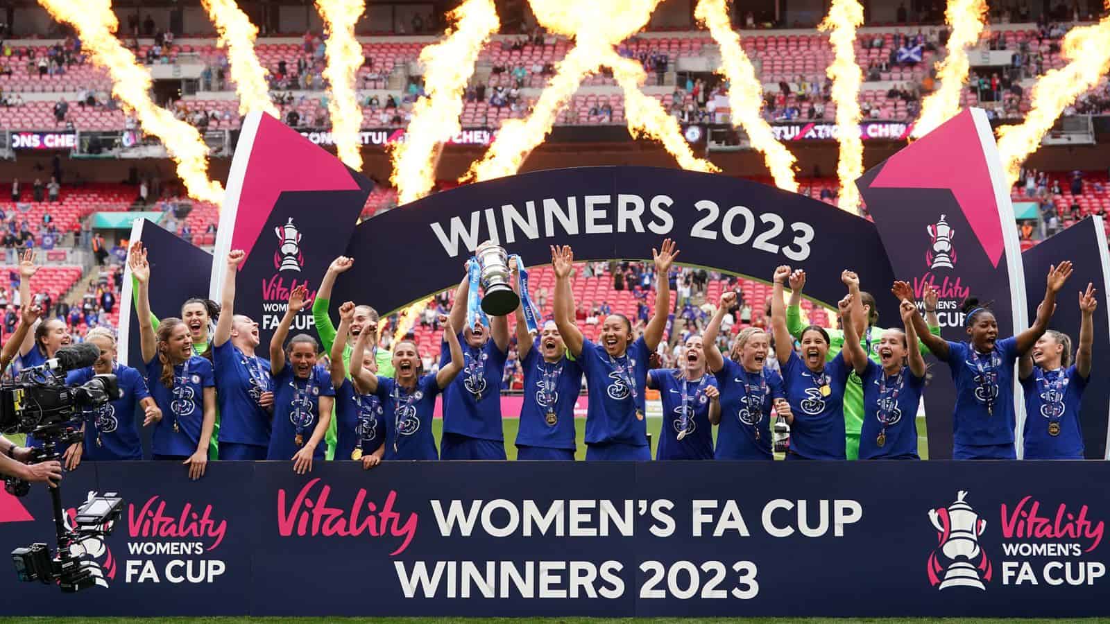 Chelsea players celebrating their victory in the FA Cup final, raising the trophy in the air amidst a backdrop of cheering fans and confetti.