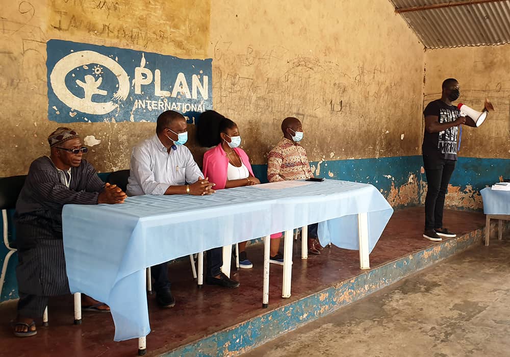 Four Plan employees sit at a table in Guinea Bissau to help families register their children’s births.  