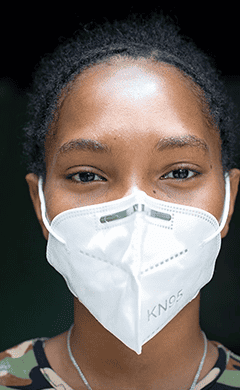 Plan International COVID-19 response page contact us section. Image depicts a young person waring a KN95 face mask.