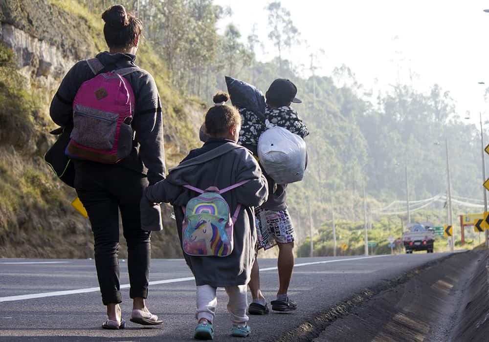 A mother, her young daughter and son walk along the side of highway, heading to Ecuador from Venezuela on foot. 