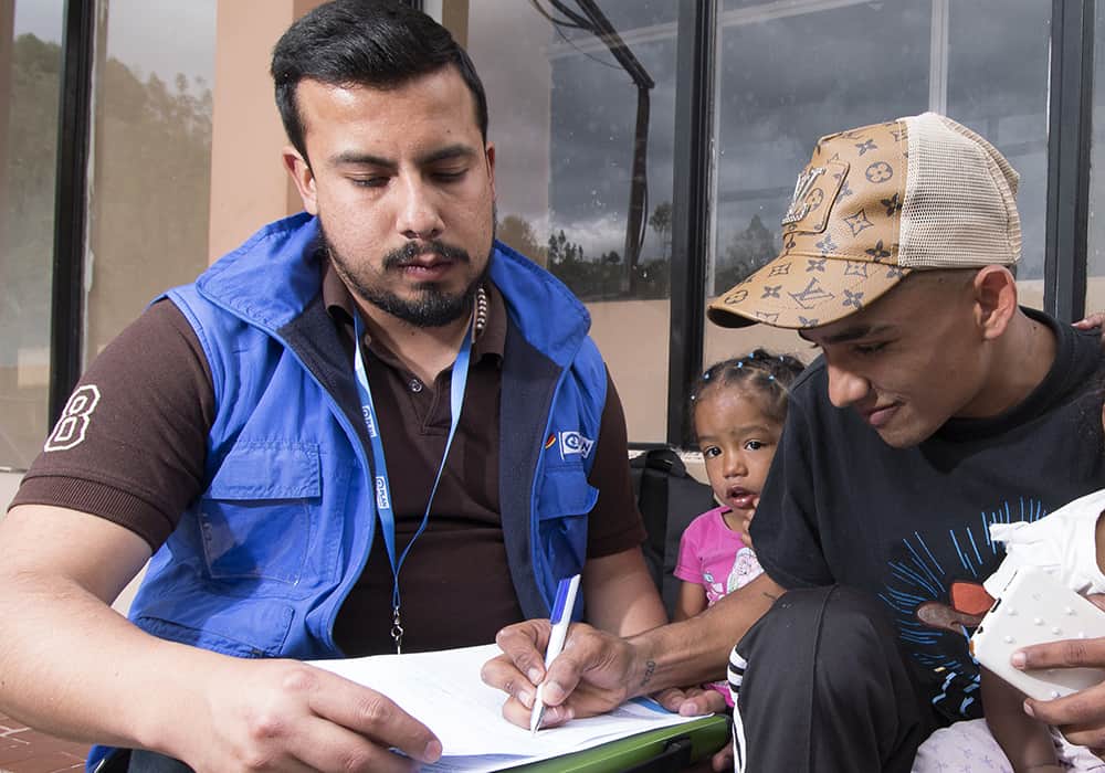A Plan humanitarian worker in Ecuador takes a Venezuelan family’s information so that they can receive cash assistance. 