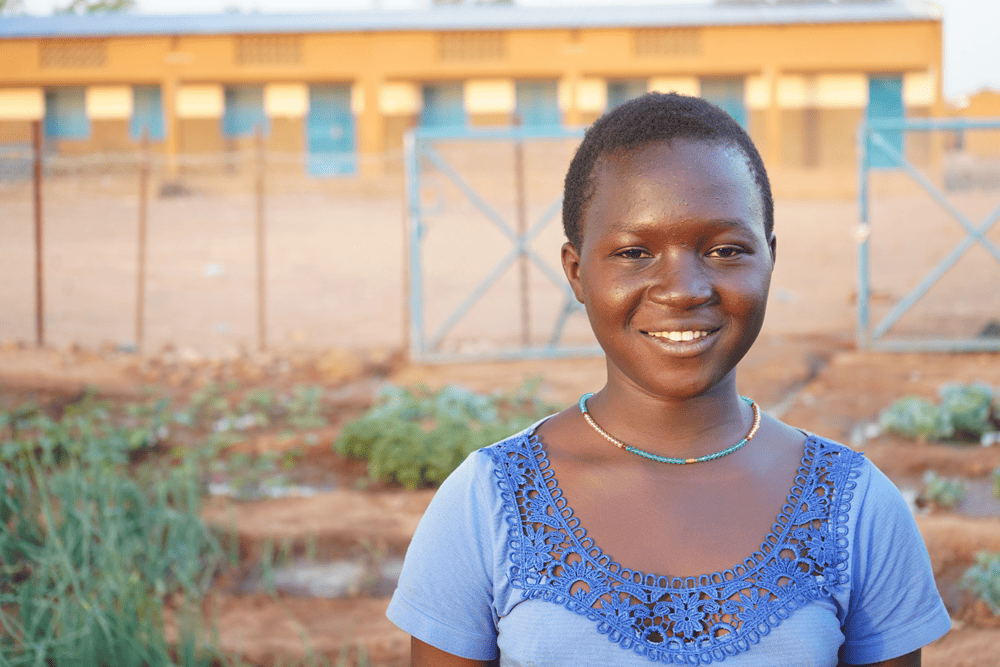 Aminata smiles as she takes a break from gardening.