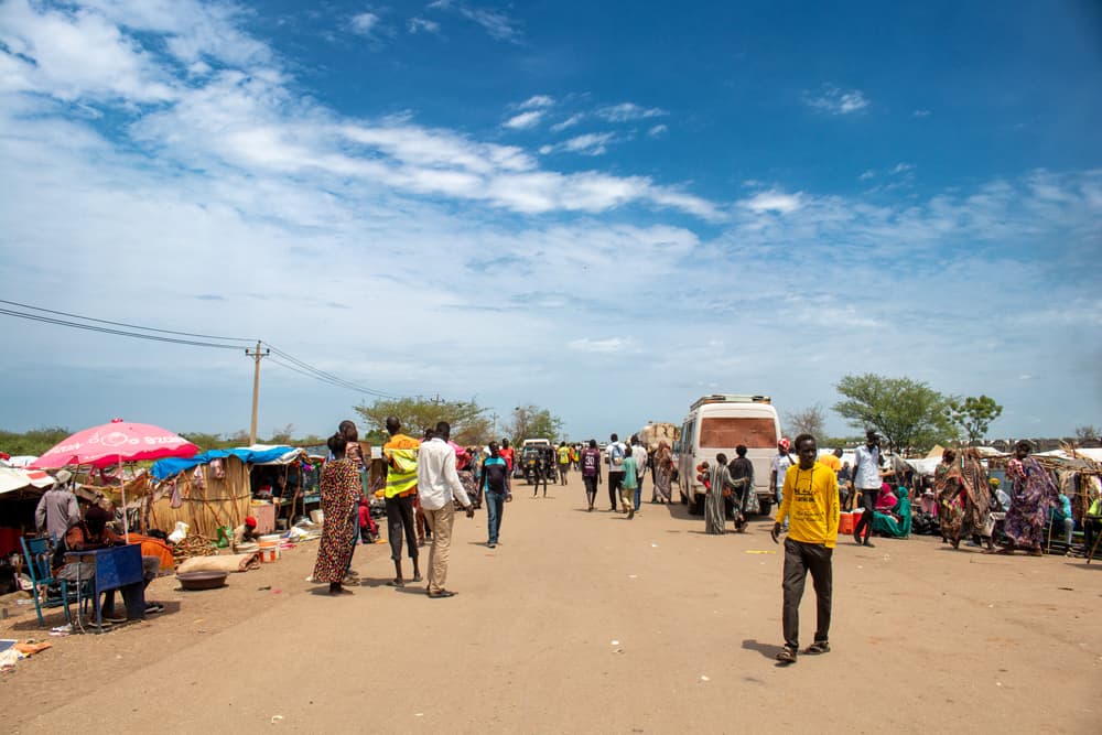 The transit center in Renk is crowded with people, buses and makeshift shelters.