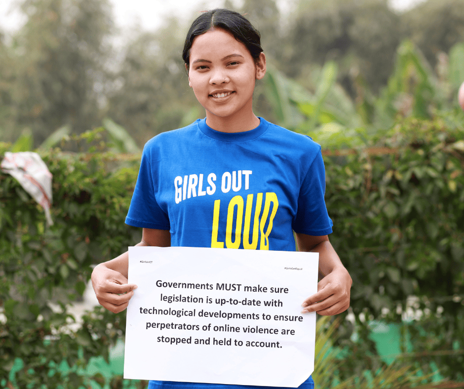 A South Asian young woman holds a white sign that reads, "Governments MUST make sure legislation is up-to-date with technological developments to ensure perpetrators of online violence are stopped and held to account." She is wearing a blue t-shirt that reads "Girls Out Loud" and stands in front of a cluster of trees.